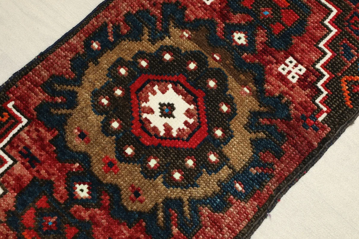 Close-up of the central medallion and surrounding geometric motifs in rust, brown, and navy