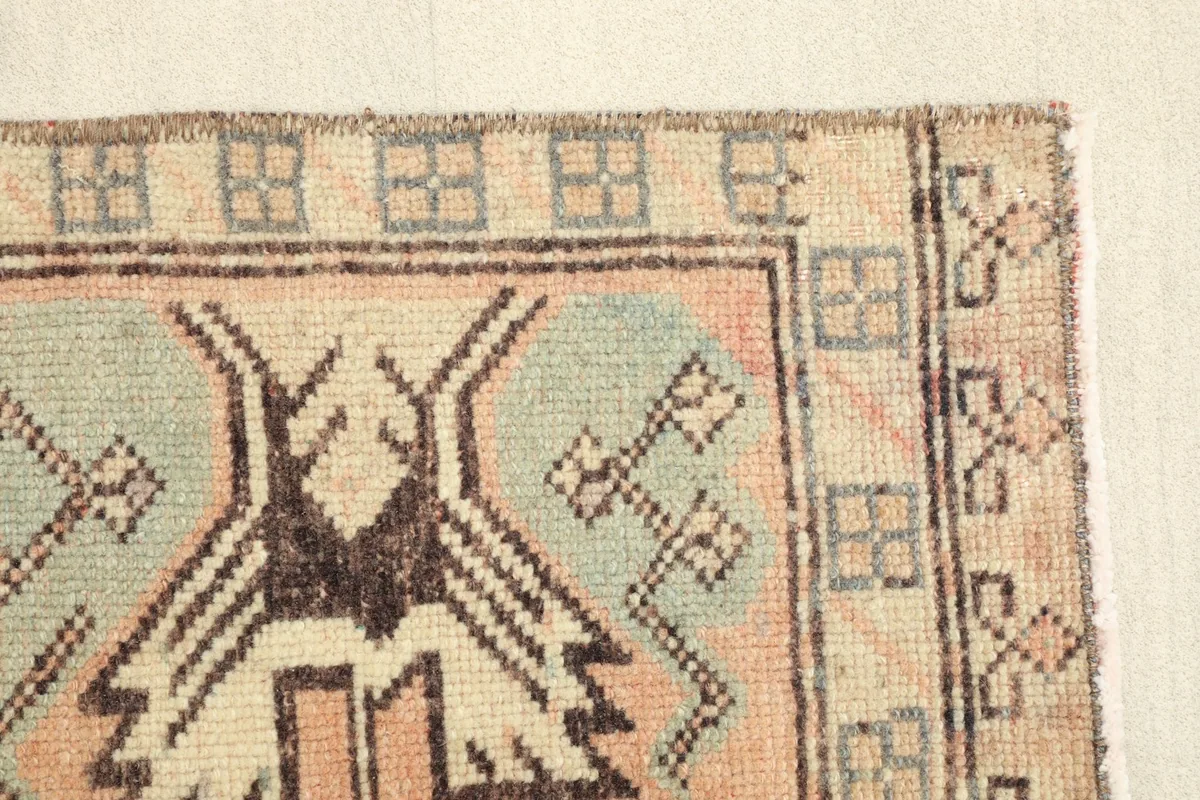 Close-up of the rug's border and a side tribal motif in beige and brown