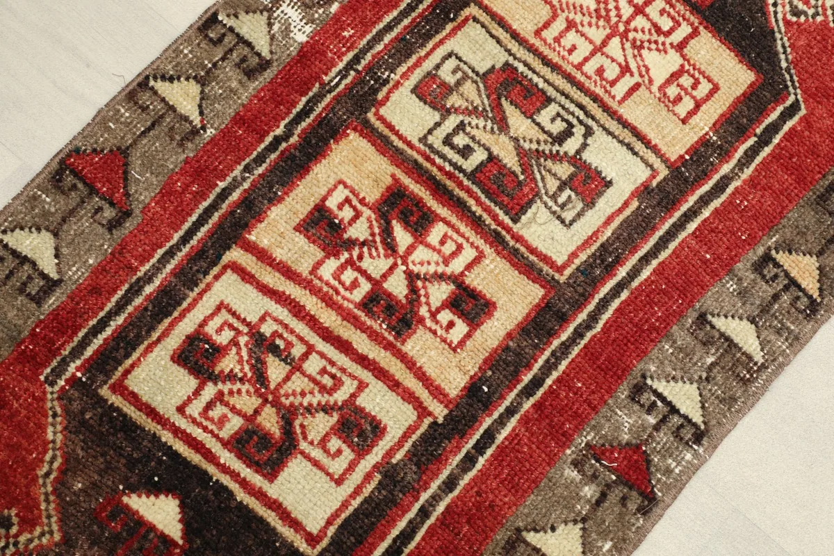 Close-up detail of the central ivory panels with red and brown geometric tribal motifs.