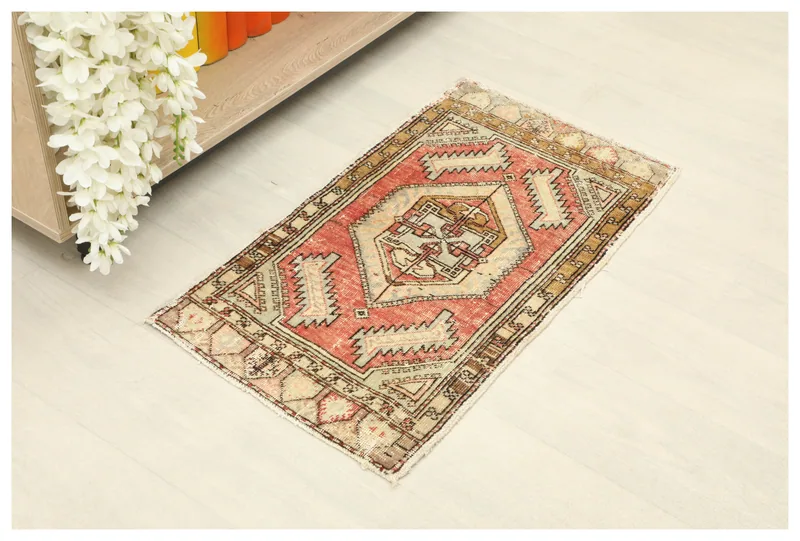 Full top view of the vintage red beige tribal Anatolian doormat on a white floor.