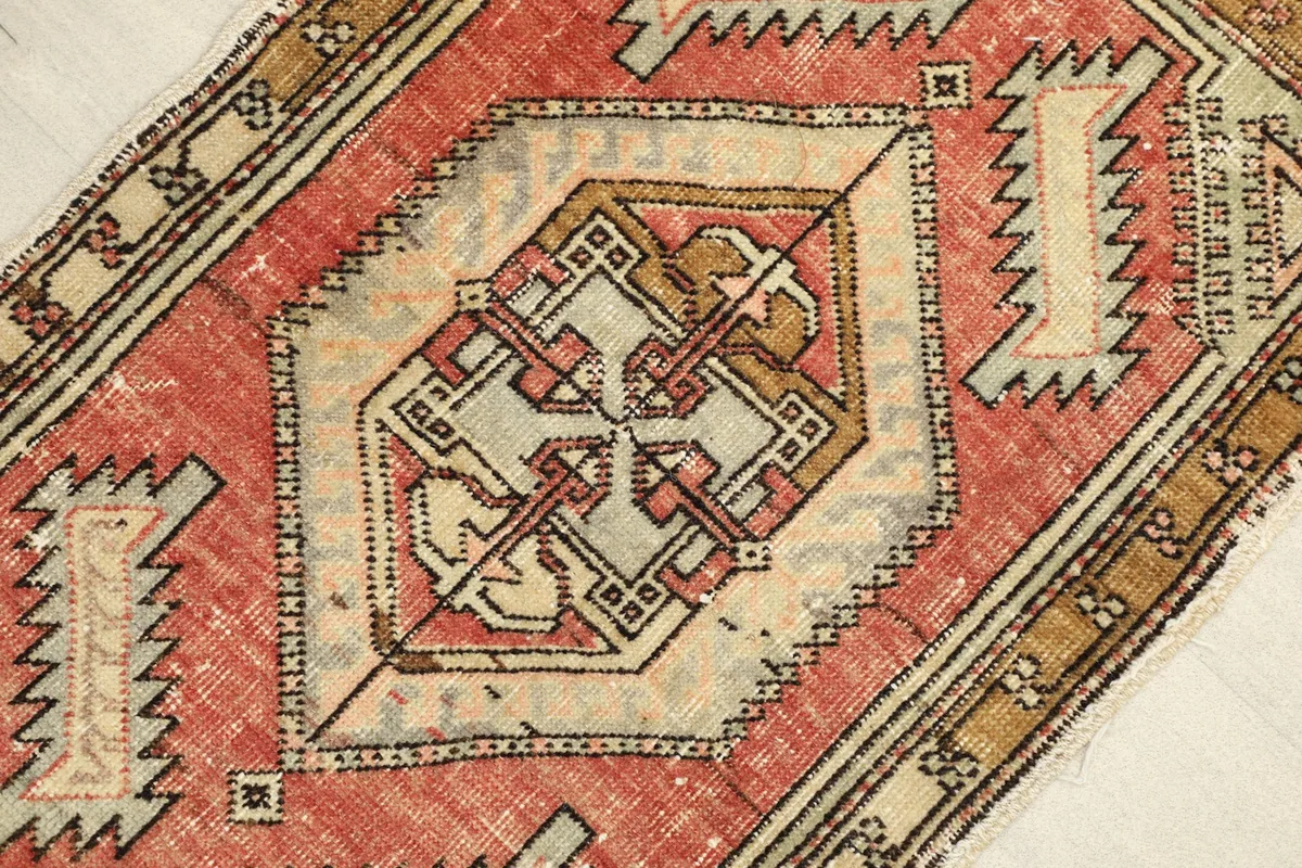 Close-up detail of the central geometric motif and surrounding patterns in red, beige, and gray.