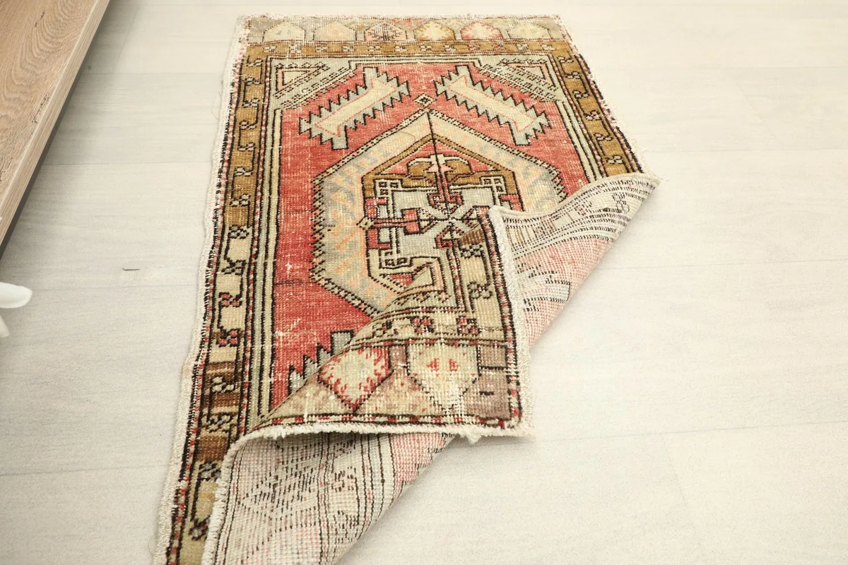 Angled view of the rug with a folded corner, demonstrating the low wool pile and texture.
