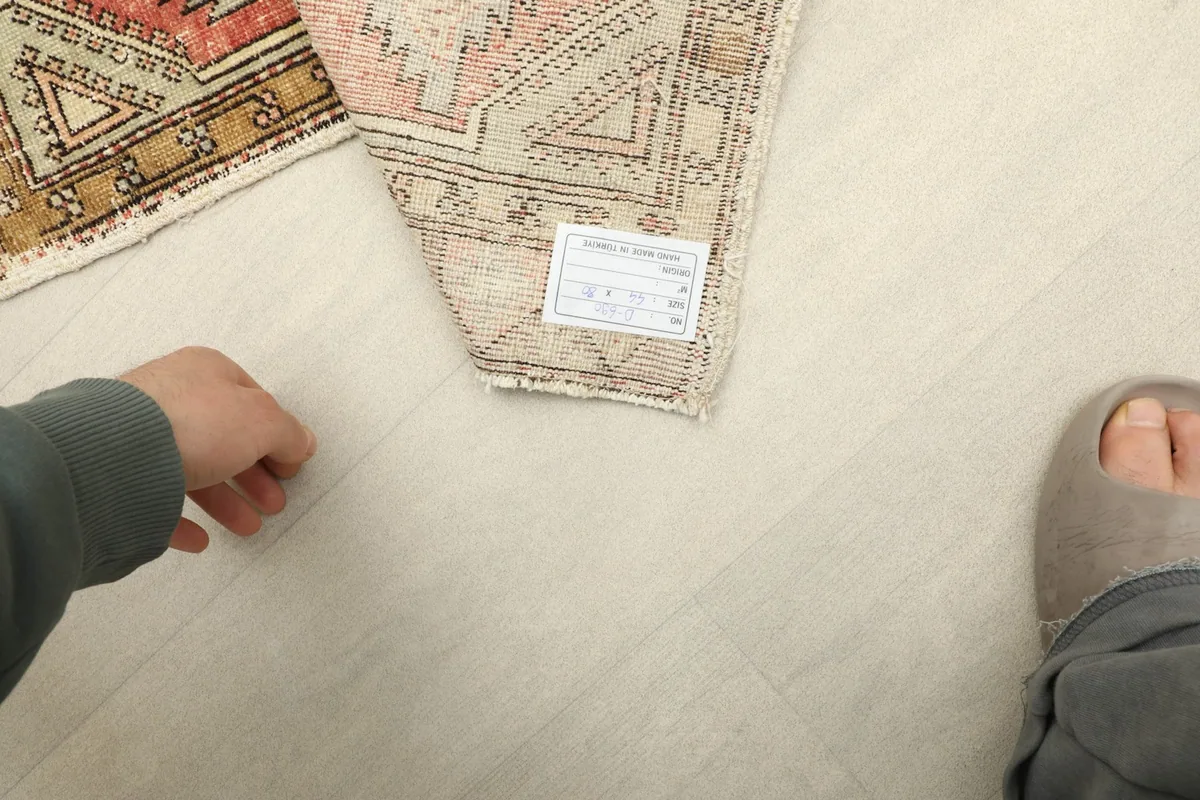 View from above showing a hand and foot next to the rug, indicating its small size.