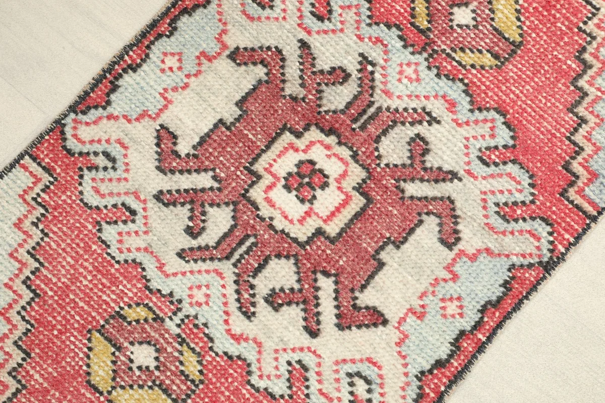 Close-up detail of the rug's central tribal medallion with rose, cream, and black geometric patterns.