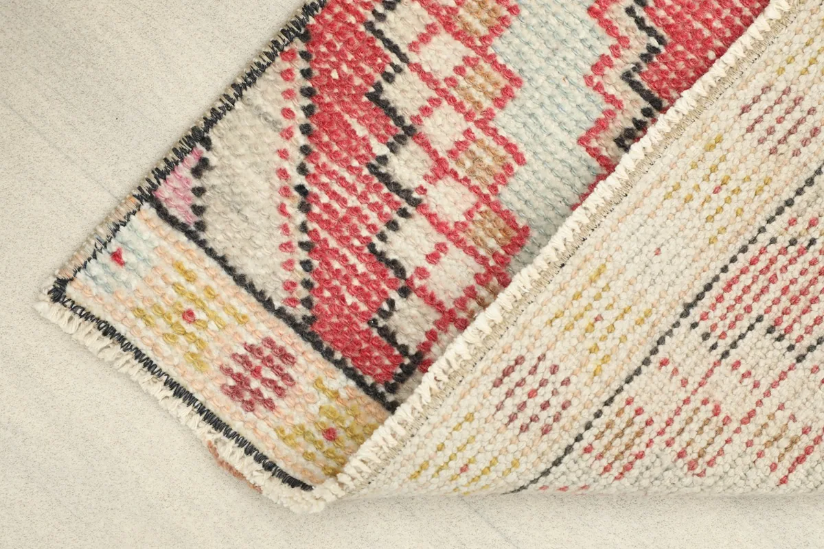 Underside view of the rug, revealing the cotton foundation and the reverse of the hand-knotted wool pile.