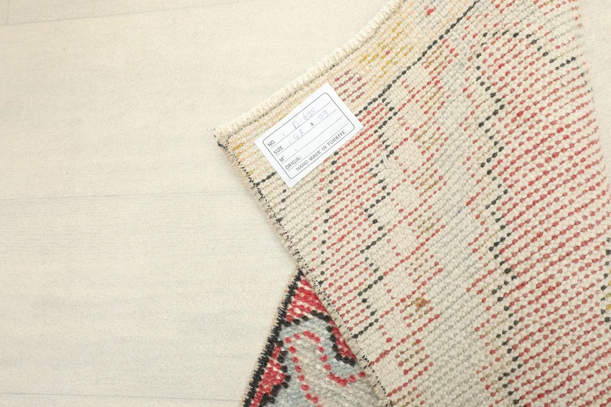 Detail of the rug's back, displaying the tight knotting and a small label on the cotton foundation.