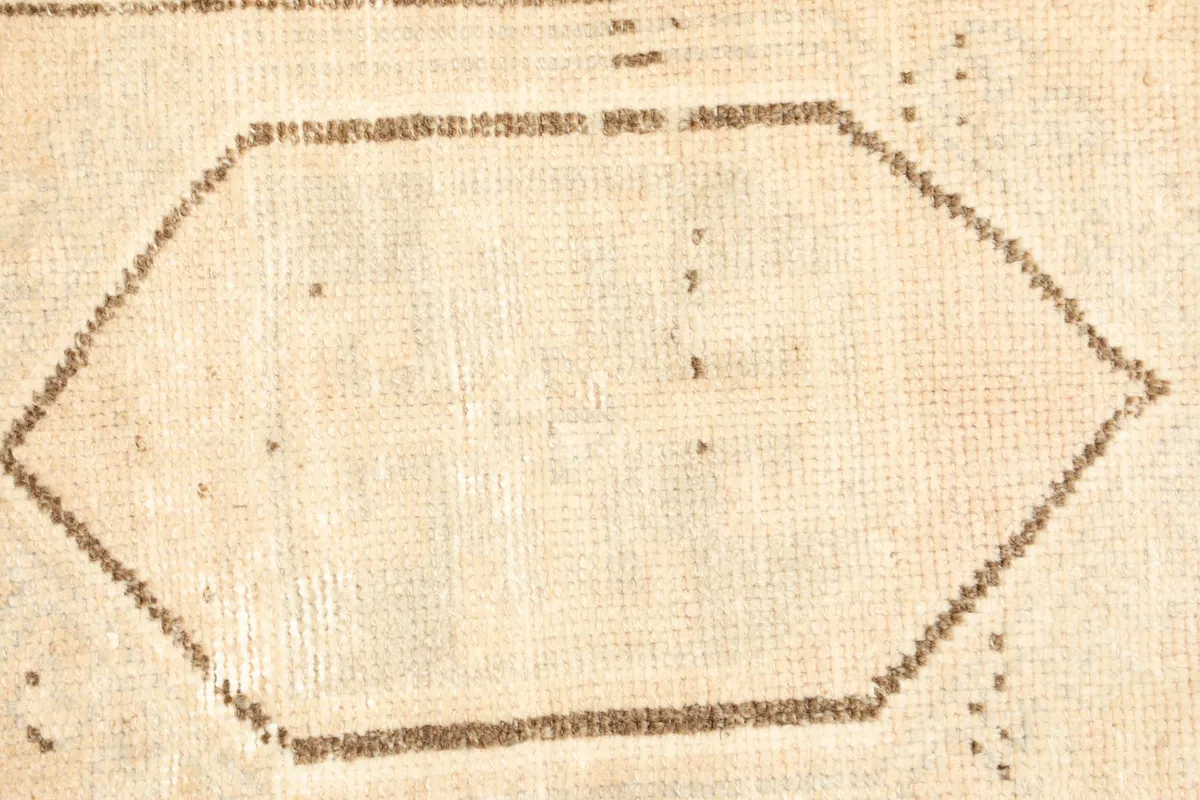 Close-up detail of the central geometric medallion and subtle texture of the wool pile