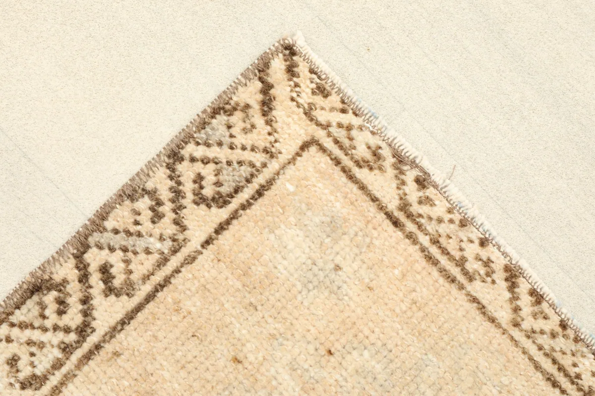 Corner detail showing the intricate brown geometric patterns along the rug's border
