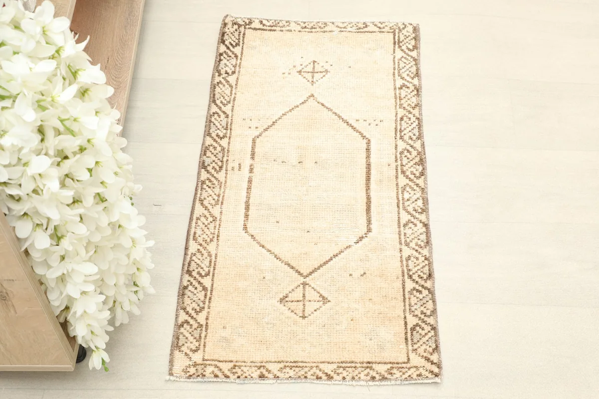 Overhead view of the vintage tan doormat showing its central geometric medallion and border