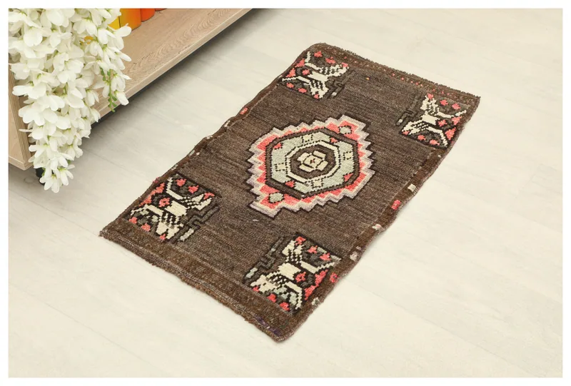 Full overhead view of the 1'5" x 2'6" brown vintage Anatolian doormat with tribal motifs on a white background.