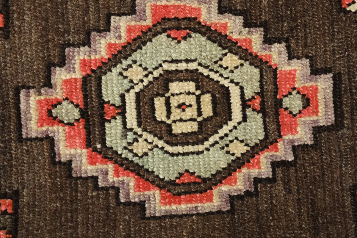 Close-up detail of the central geometric medallion, revealing the hand-knotted texture and color variations.