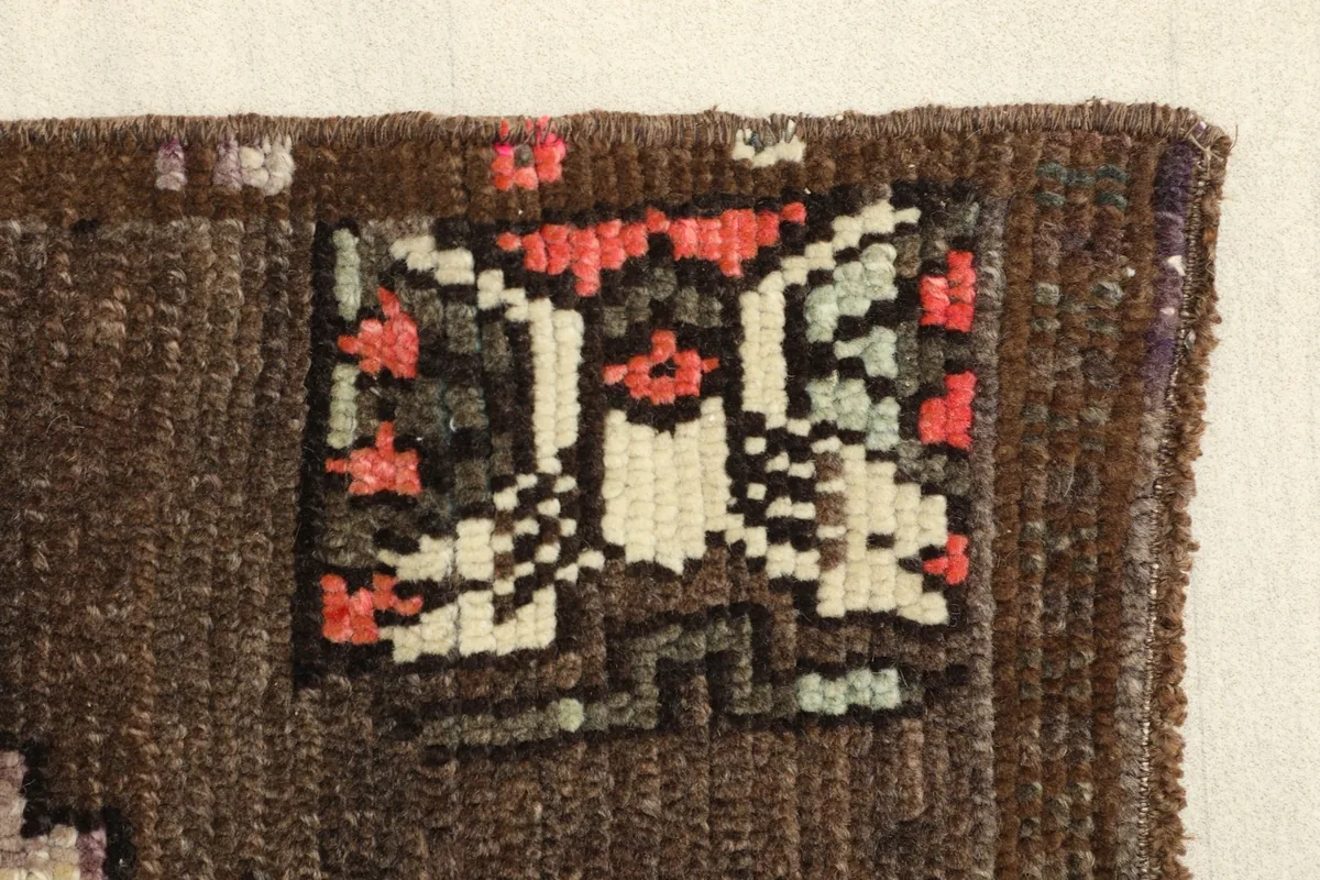 Close-up of a tribal motif in the corner, featuring stylized shapes in rose, ivory, green, and black.