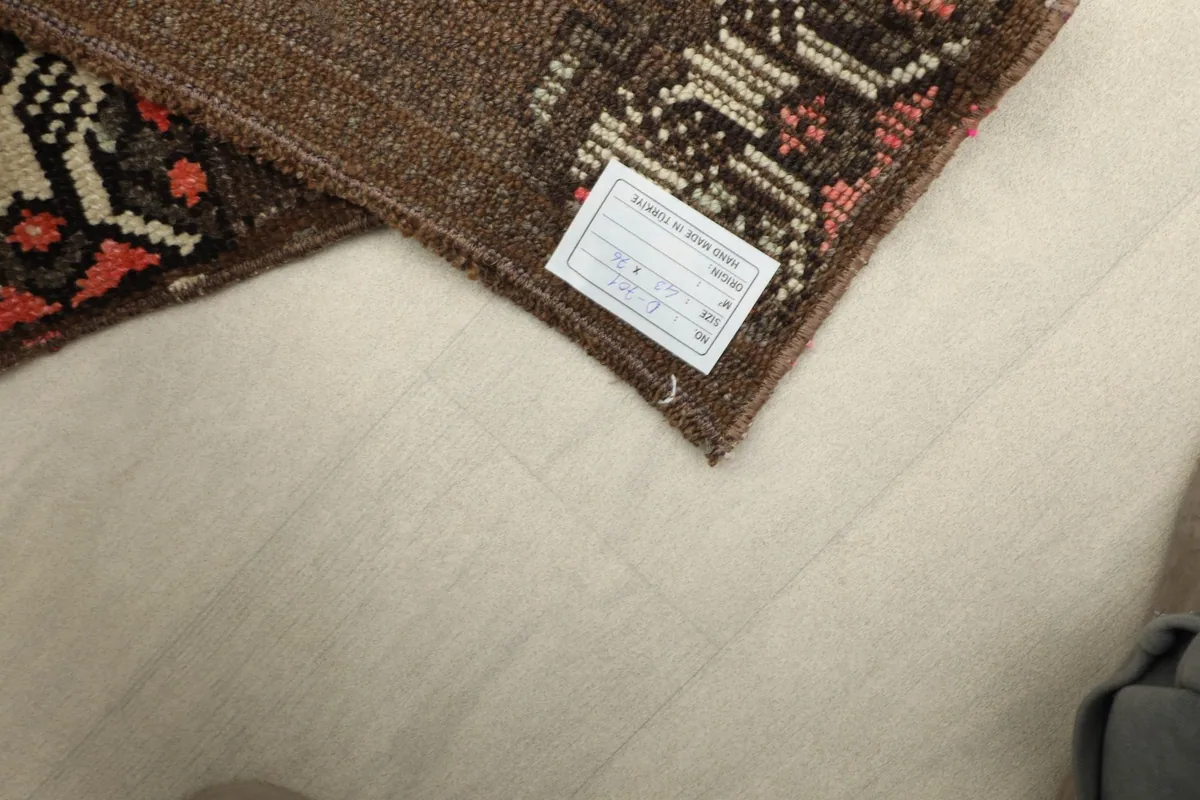 View of the back of the rug near a corner, showing the cotton foundation and a small product label.