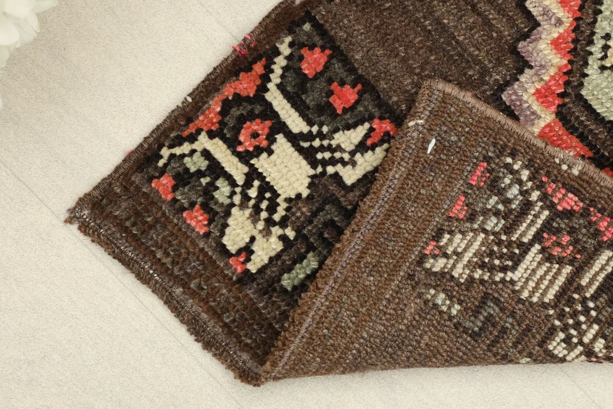 Partially folded view of the doormat, showing the back of the rug and the density of the hand-knotted wool pile.