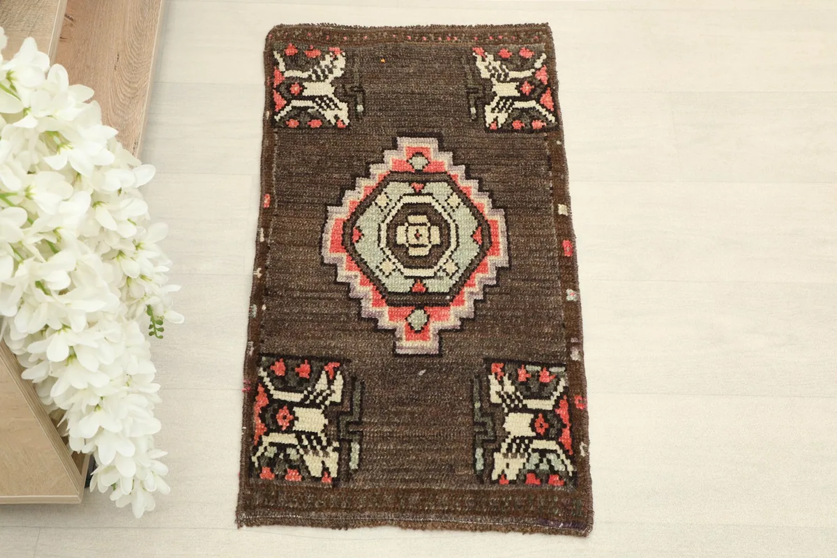 Direct overhead shot of the brown vintage doormat, showcasing its central geometric medallion and corner motifs.