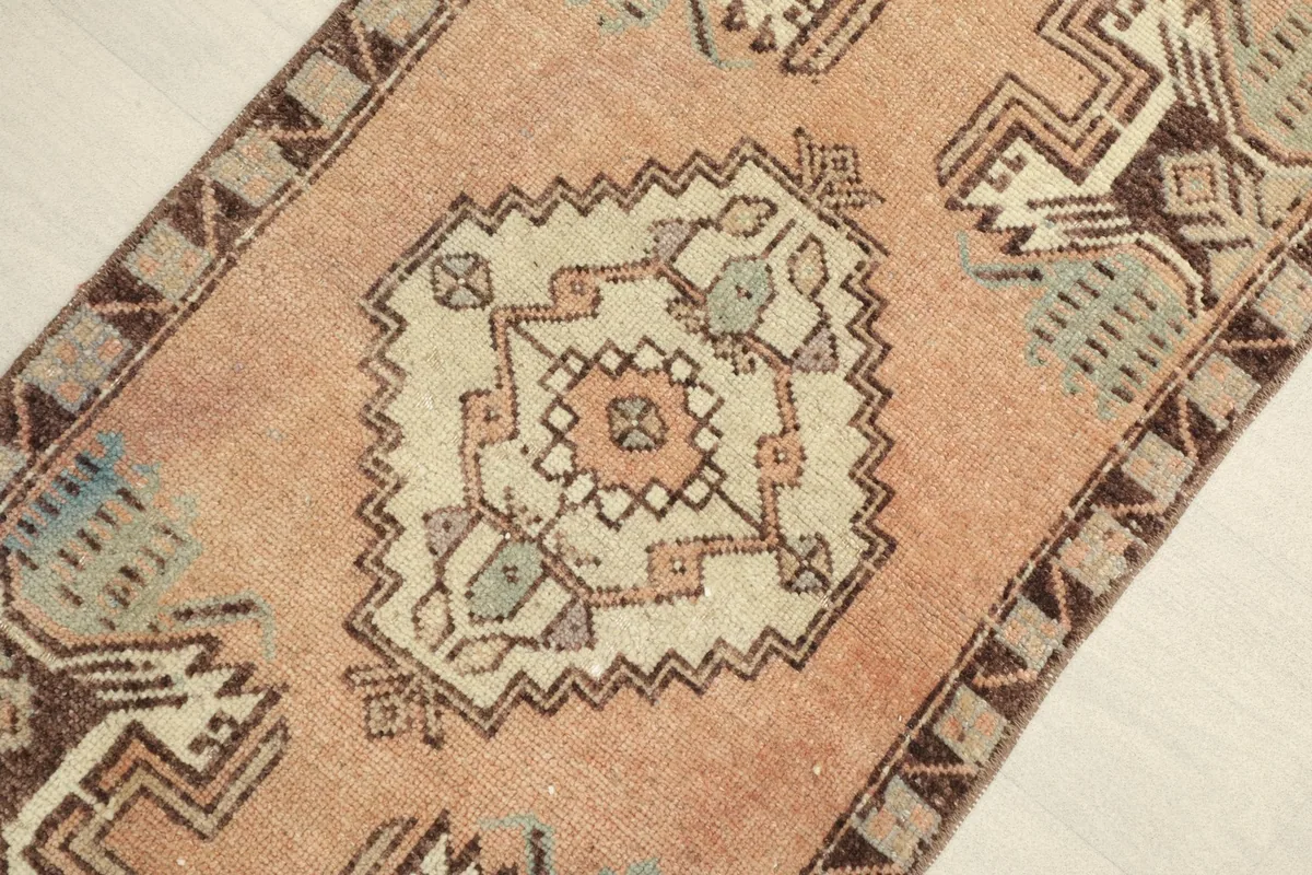 Close-up view focusing on the central medallion and surrounding geometric motifs in rose, beige, and brown.