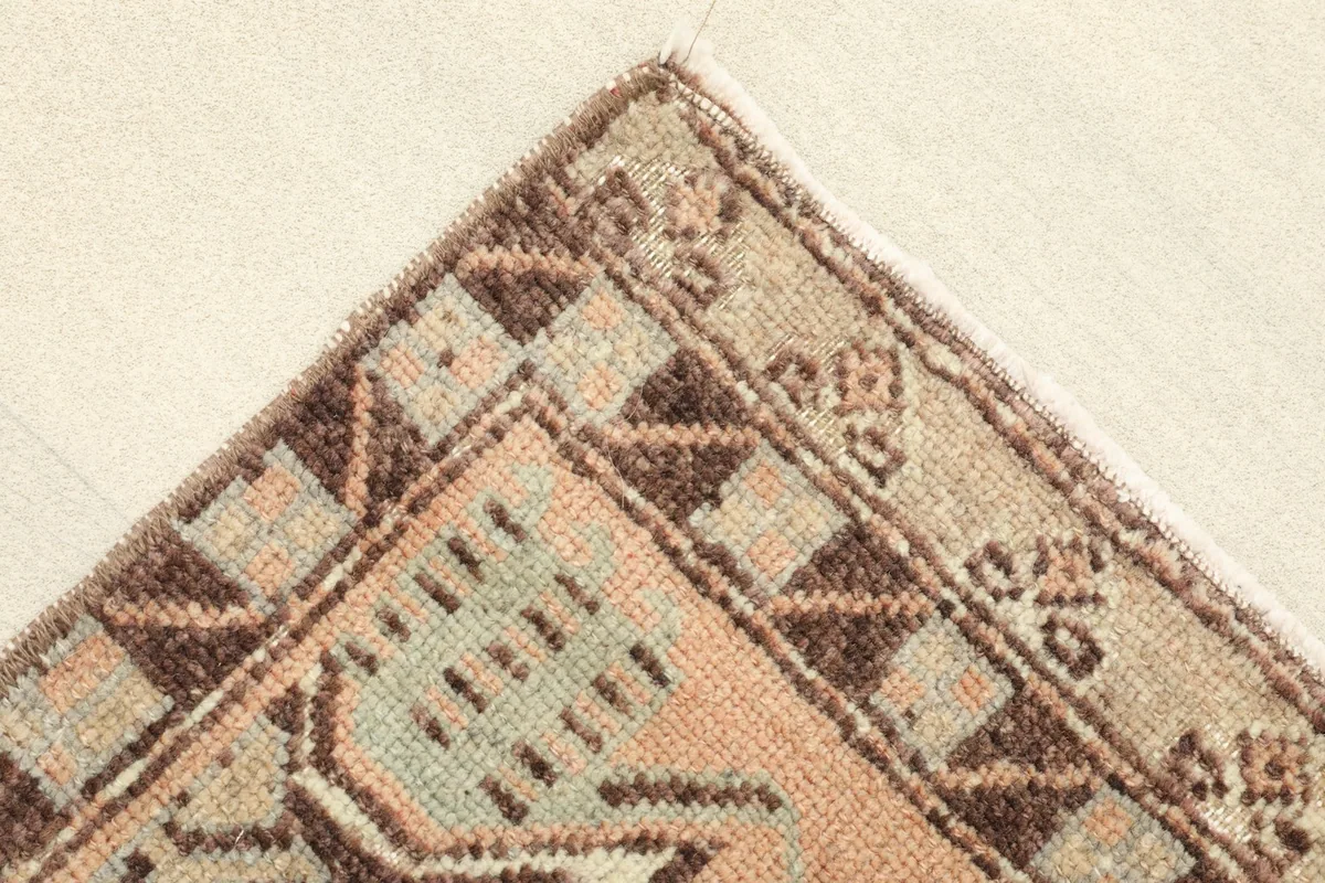Corner detail of the rug, showing the border pattern and the edge finishing.