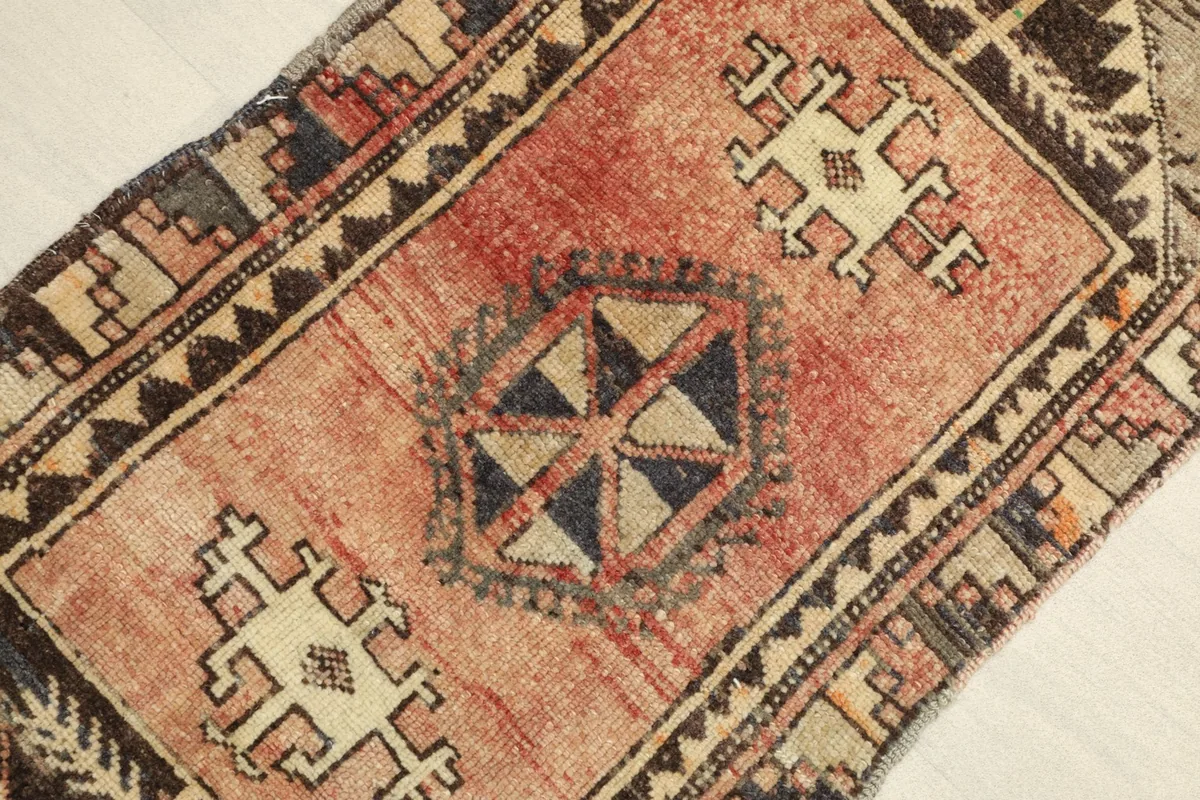 Close-up view of the rug's central geometric medallion in navy and tan against the rose field.