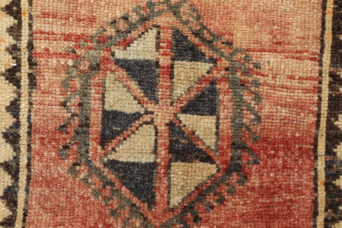 Detailed shot of the intricate geometric pattern and color variations within the rug's center.