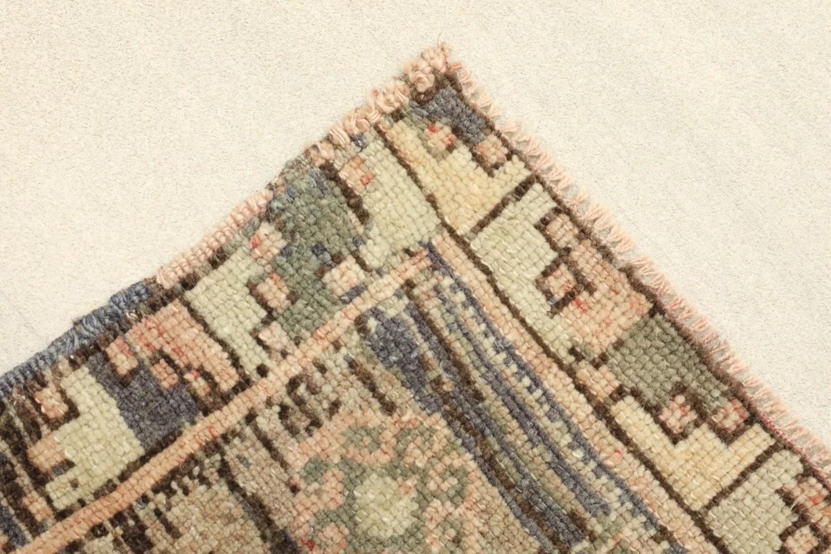 Corner view showing the rug's border design with green, cream, and brown geometric motifs.