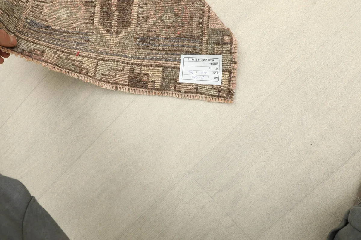 Rug corner with a label, indicating its origin and material, held by a hand.