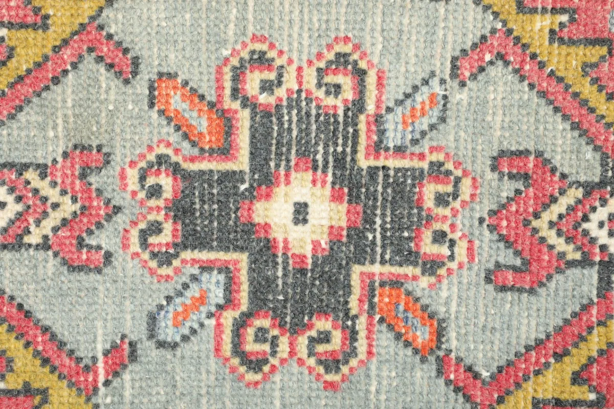 Detailed close-up of the vintage rug's central motif, highlighting the intricate knotting and color variations.