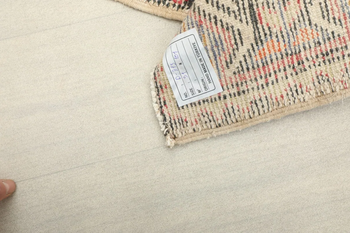 Close-up of the rug's reverse side, showing the cotton foundation and a product tag.