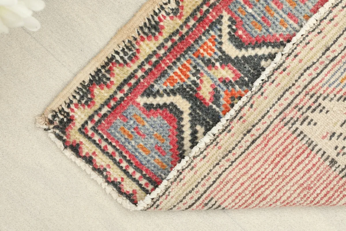 View of the doormat folded over, showcasing the reverse side of the hand-knotted cotton foundation.