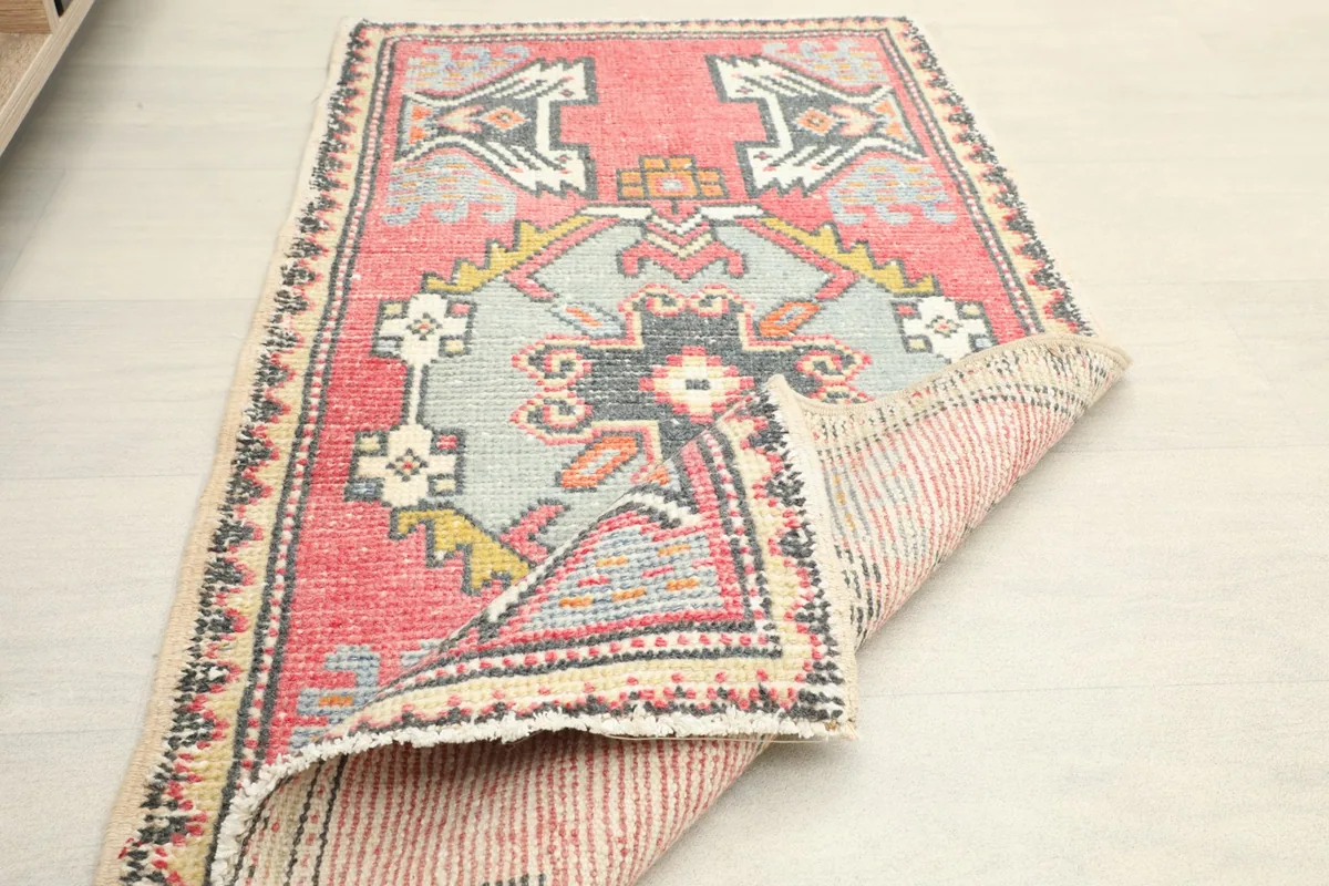 Angled view of the rug with one corner folded back, displaying the tight weave of the backing.