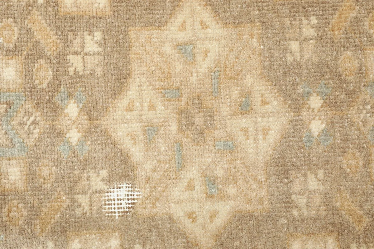 Close-up detail of the rug's central pattern and areas of wear, revealing the cotton foundation