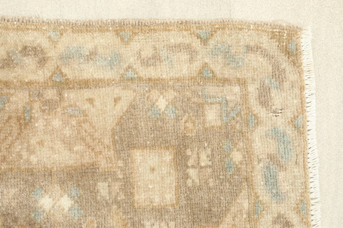 Close-up of the rug's edge, highlighting the distressed pile and original fringe