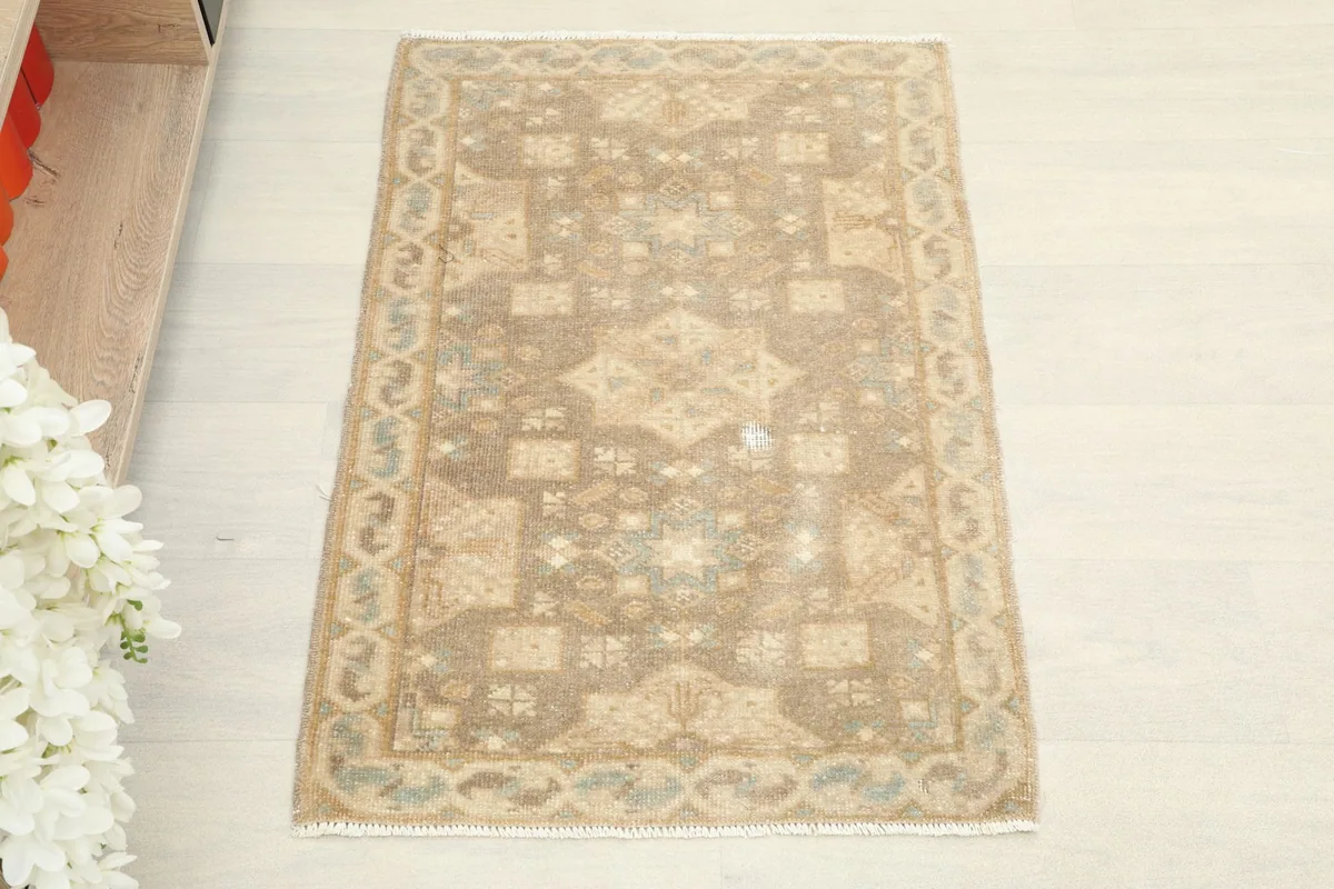Top-down view of the tan and brown vintage rug, showing its overall geometric pattern