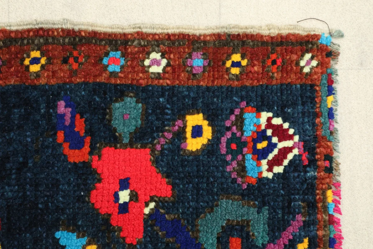 Side border detail of the rust frame and the contrasting navy field with colorful motifs