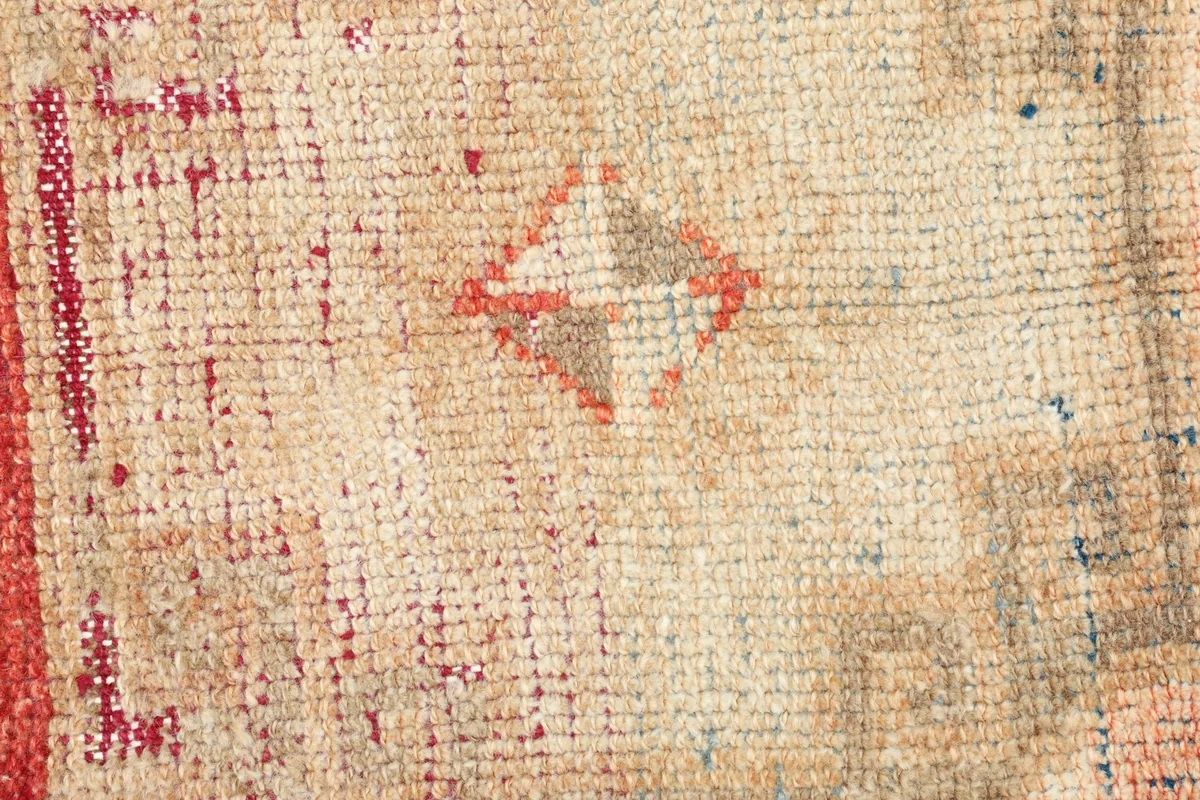 Detailed view of the wool pile and specific geometric motif with red, beige, and brown threads.