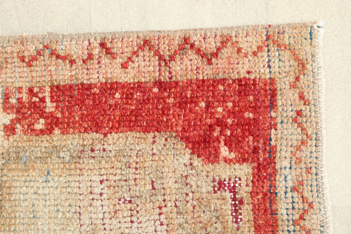Detail of the rug's side border, displaying the red and rust hues and the hand-knotted texture.