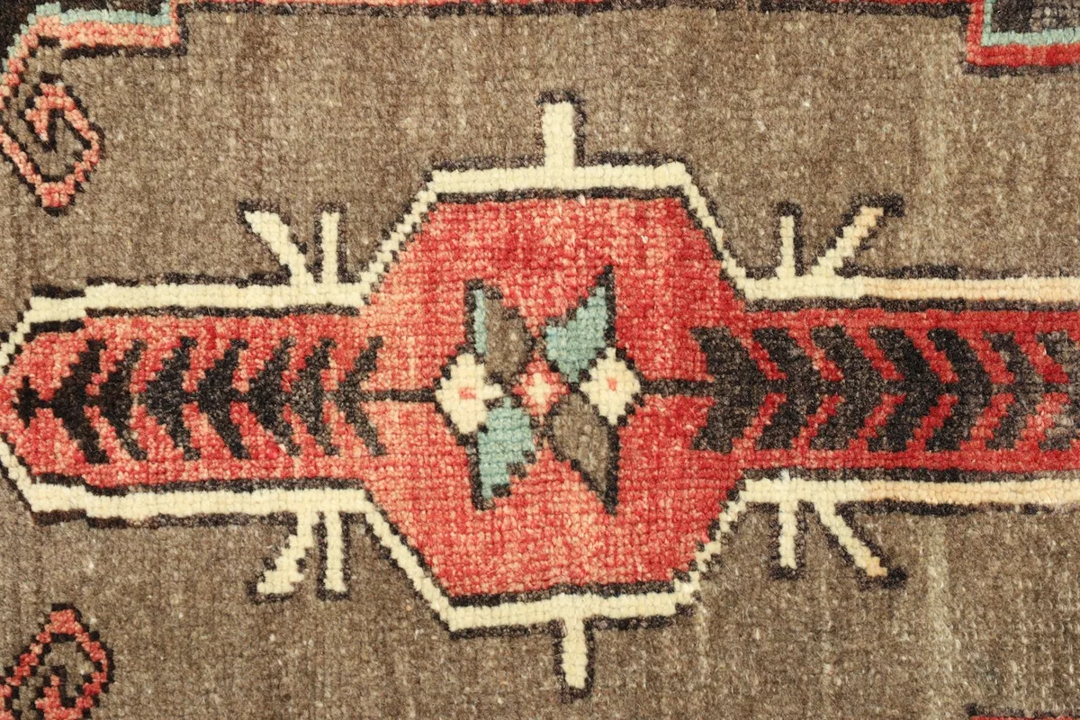 Detailed close-up of the central geometric motif in red, brown, black, and blue tones.