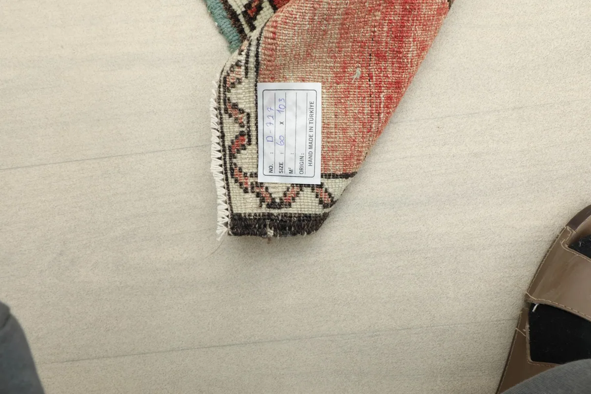 View of the rug's back, showing the cotton foundation and a product label.