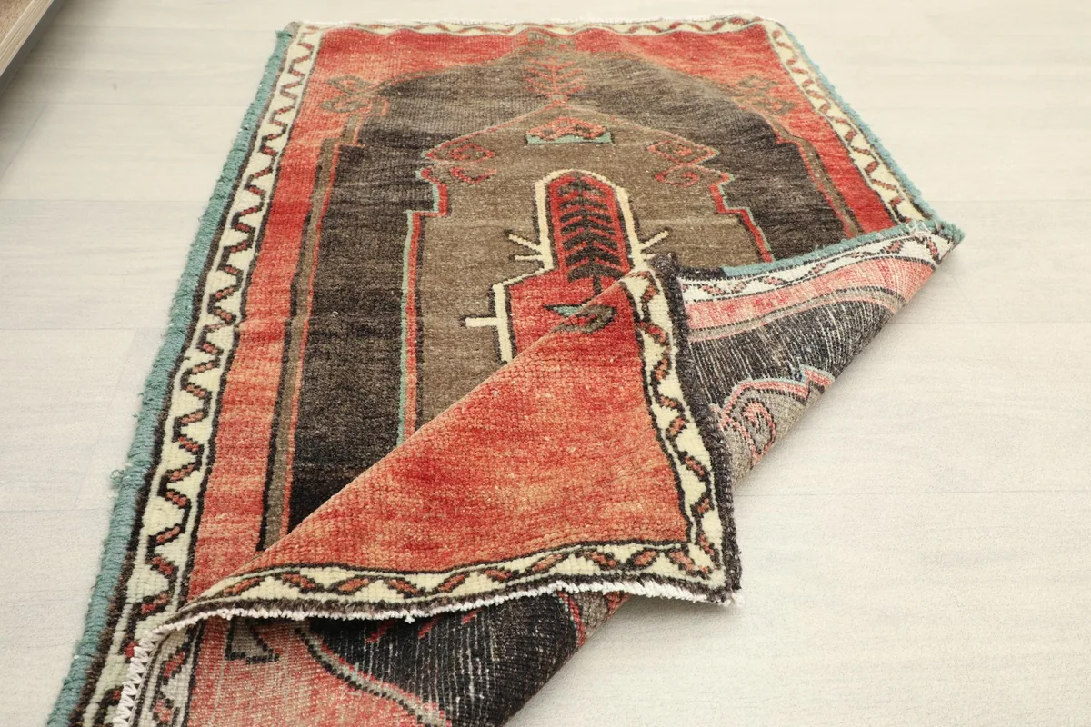 Partial fold of the rug, showing the wool pile and the overall vintage condition.