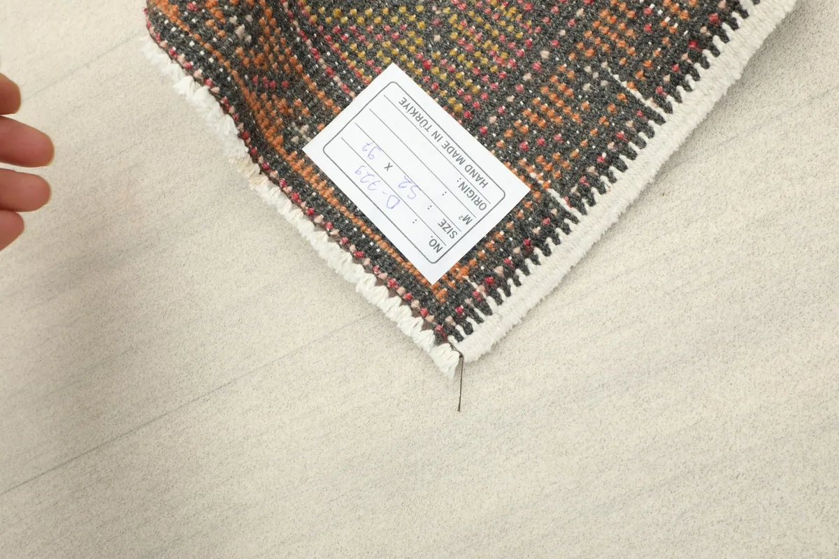 Underside of the rug with a label, showing the hand-knotted texture and cotton foundation