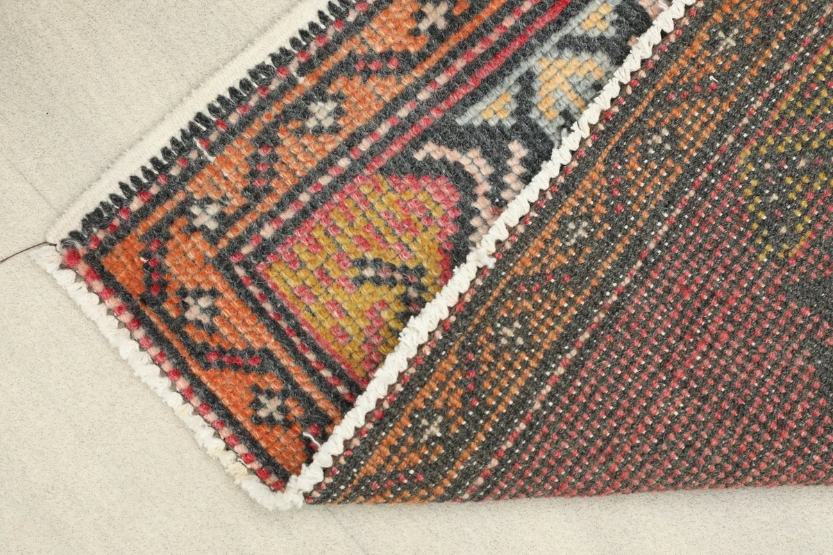 View of the rug folded to show the cotton foundation and the reverse side pattern