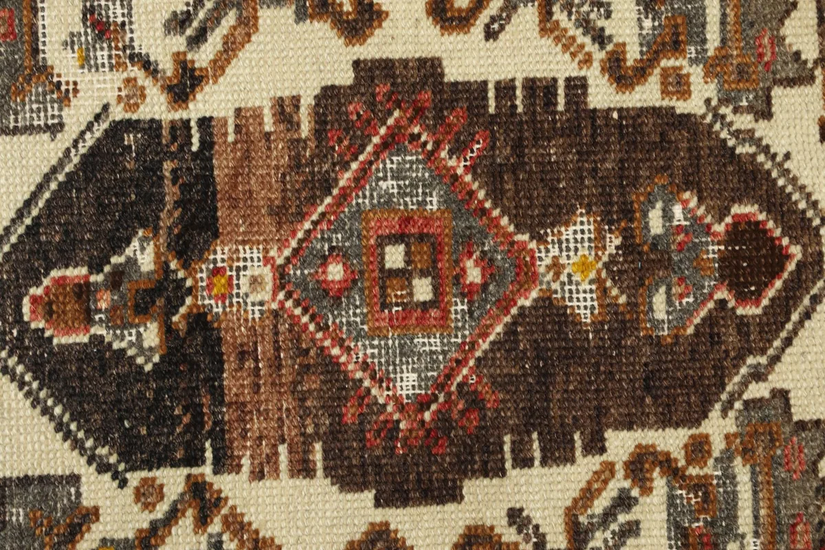 Detailed view of the central geometric design in cream, brown, and gray, showing knotting.