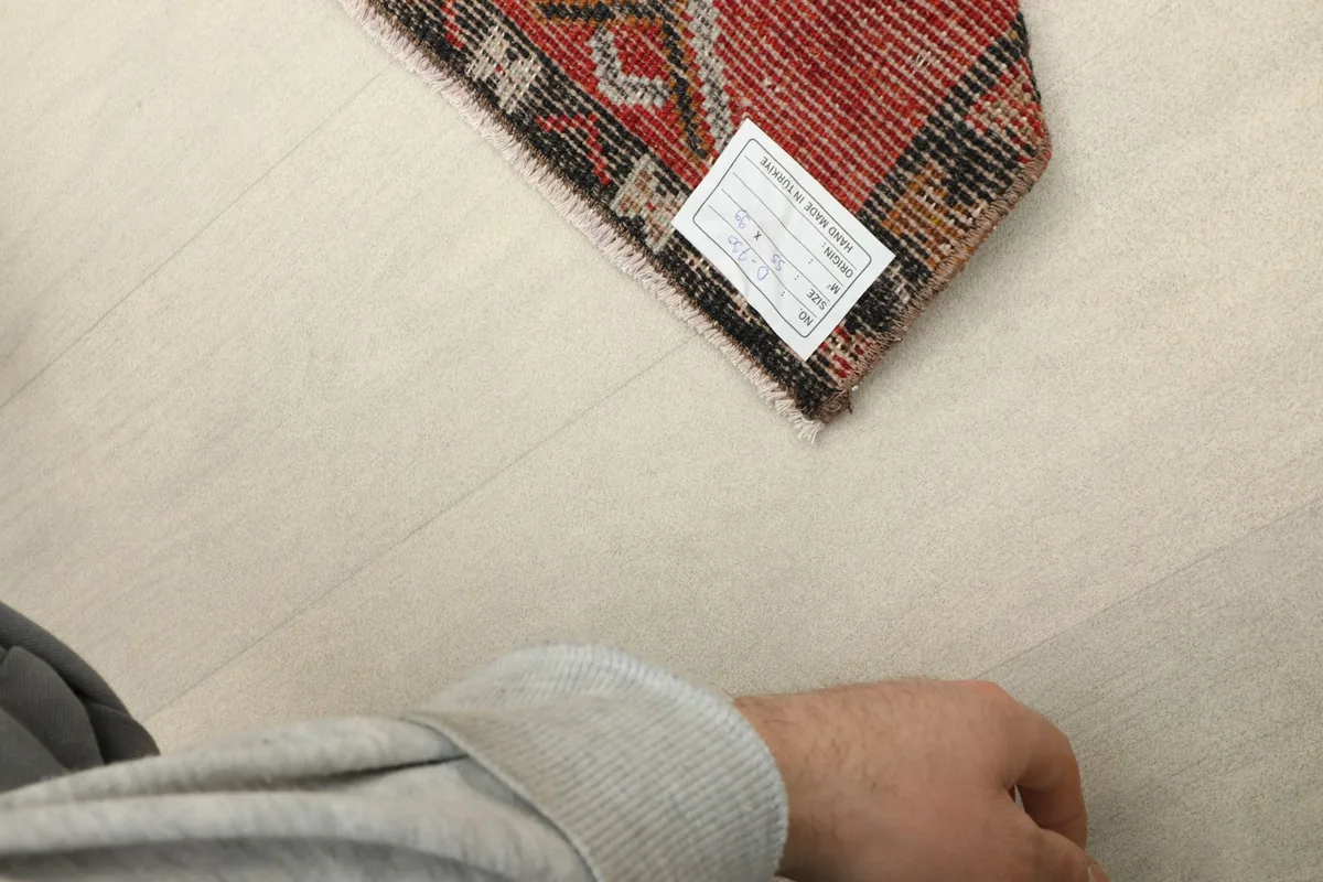 Underside of the rug corner, revealing the hand-knotted cotton foundation and a product label.