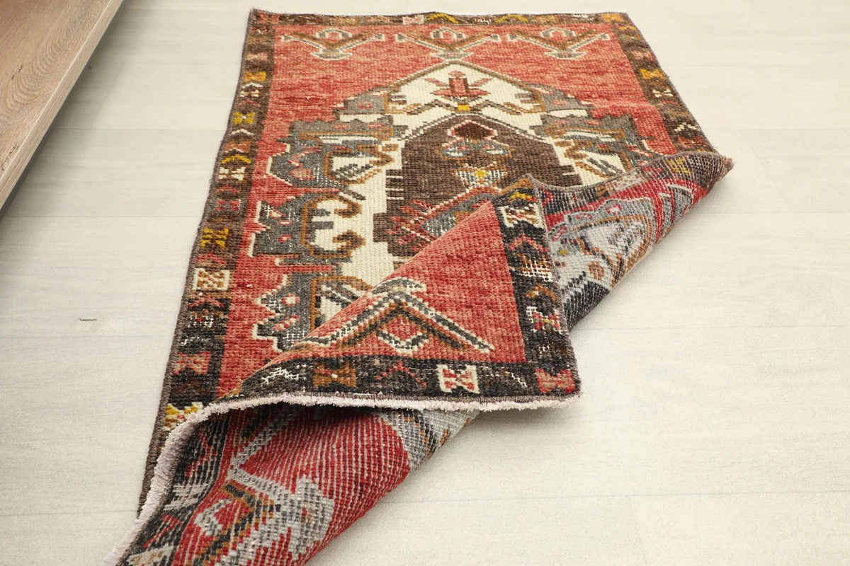 The rug partially folded, displaying its full design and the softness of the vintage wool.