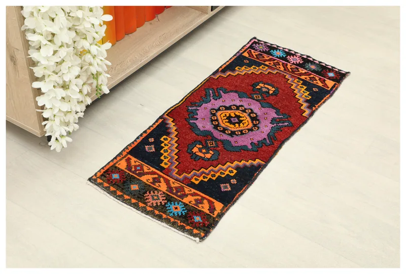 Full top view of the 1x3 vintage red and navy tribal runner on a white floor.