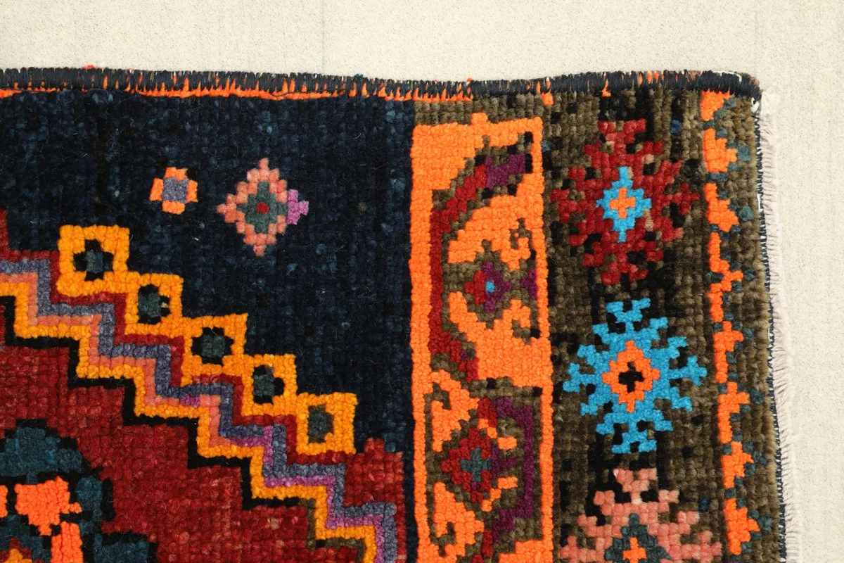 Detail of the rug's edge, revealing the hand-knotted construction and varied border patterns.