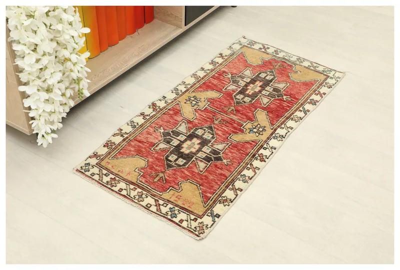 Full overhead view of the 1'8" x 3'6" red and tan vintage Anatolian wool rug on a light floor.