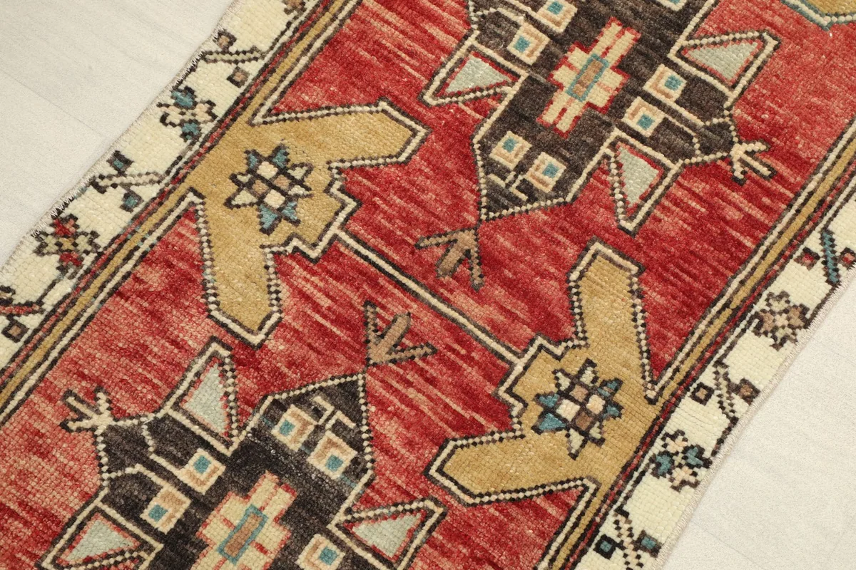 Close-up view of the rug's red field and tan border, showing the intricate tribal patterns and texture.