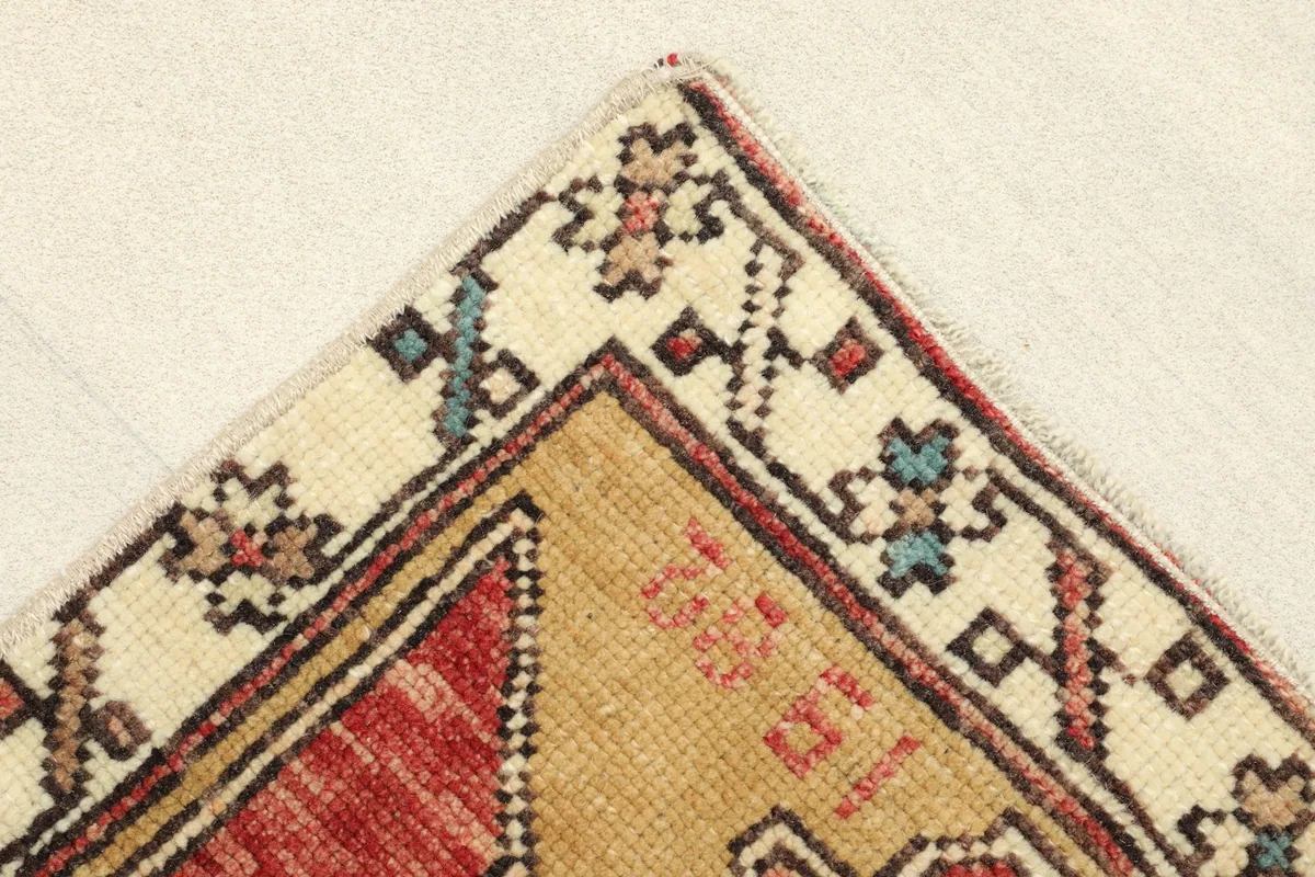 Corner detail of the rug, showcasing the ivory border with small colorful geometric designs.