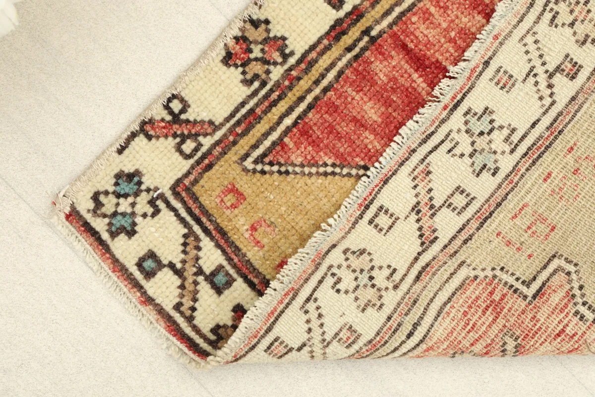 View of the rug's low pile and the cotton foundation, showing the reverse side's simple pattern.