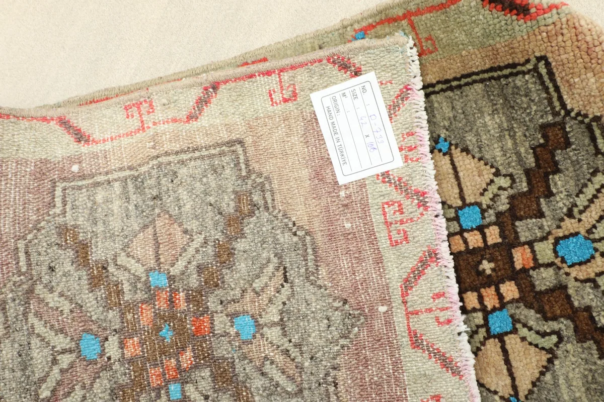 Close-up of the rug's back, showing the hand-knotted wool pile on cotton foundation and a product label.